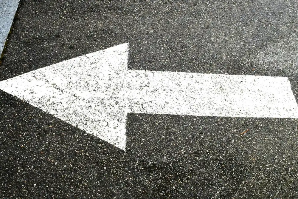 Bright white direction arrow on fresh asphalt